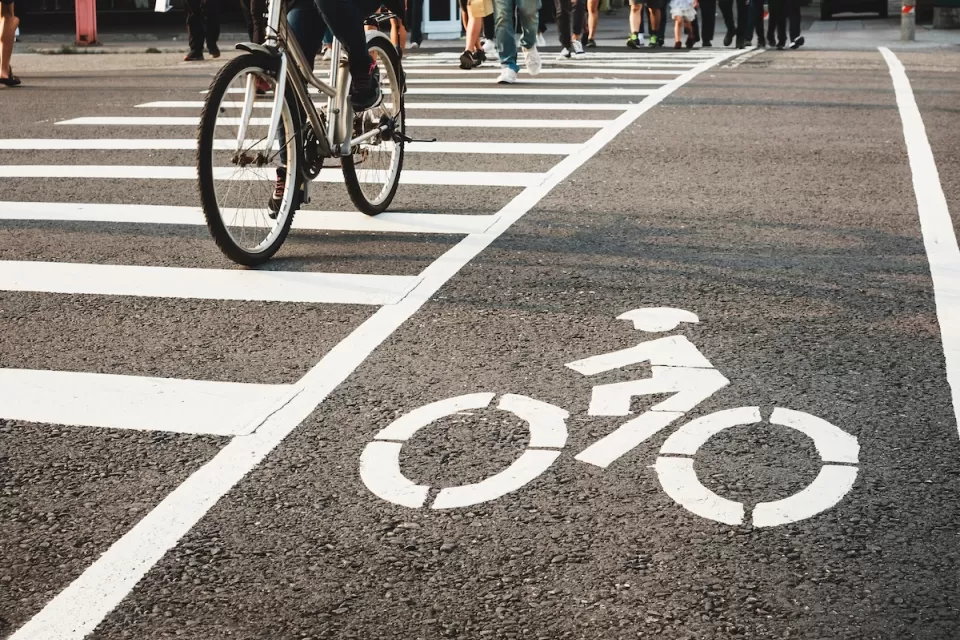 Low angle of pedestrians and a bicycle crossing the street at an urban crosswalk.